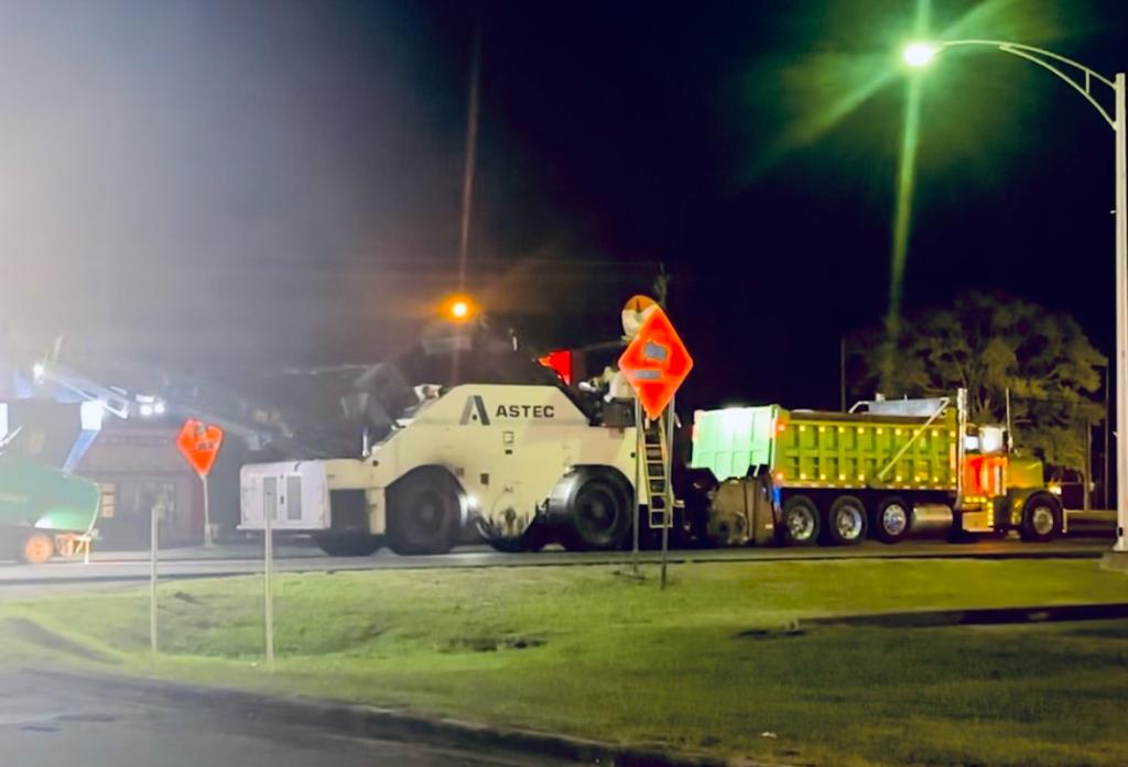 Green Peterbilt dump truck hauling asphalt millings alongside an Astec milling machine on Highway 431 in Boaz, AL at night