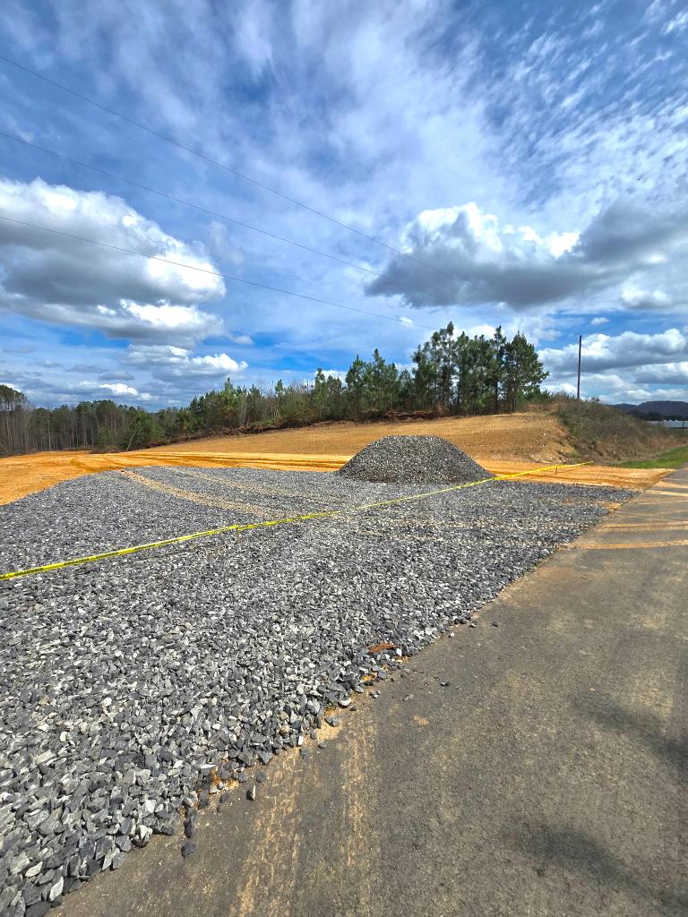Spreading gravel on a job site with a green Peterbilt dump truck