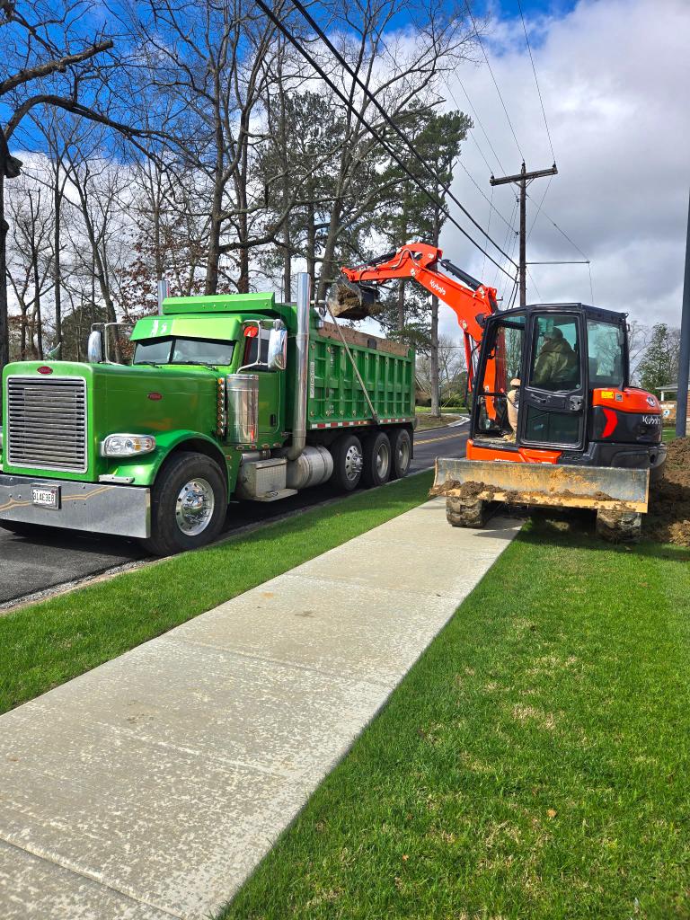 Kubota excavator loading green Peterbilt dump truck on a haul off job
